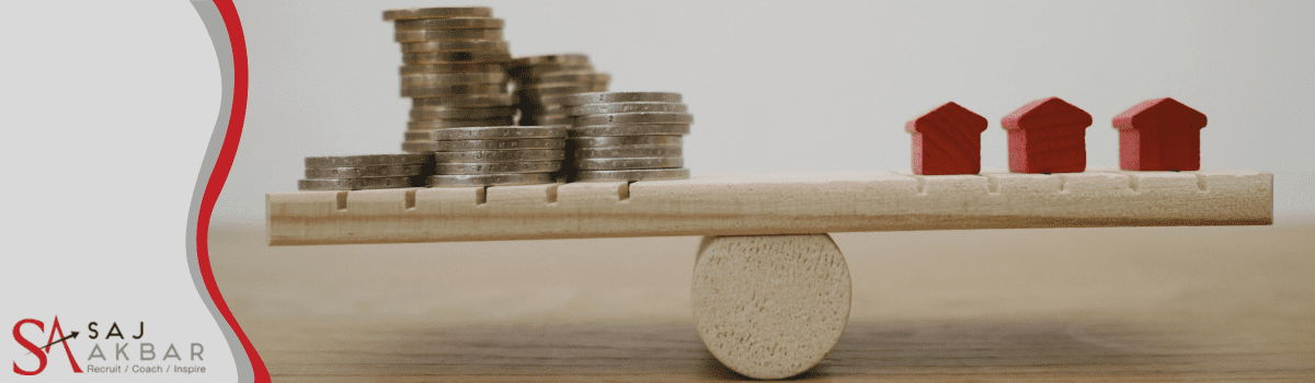 A balanced scale with money on one side and red houses on the other